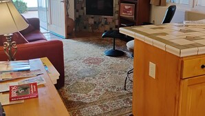 A cozy living room with a fireplace, a red sofa, a coffee table with books, and a TV. - 1/2 mile from large bike/walk path  and 3 miles from the U of A (Tucson)