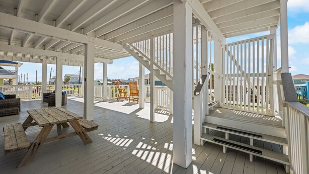 A covered outdoor deck with wooden benches and a staircase.