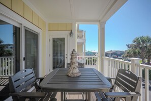 Un balcon avec une table et des chaises, une structure décorative en pierre et une vue sur l’océan et les bâtiments qui se dressent à l’arrière-plan.