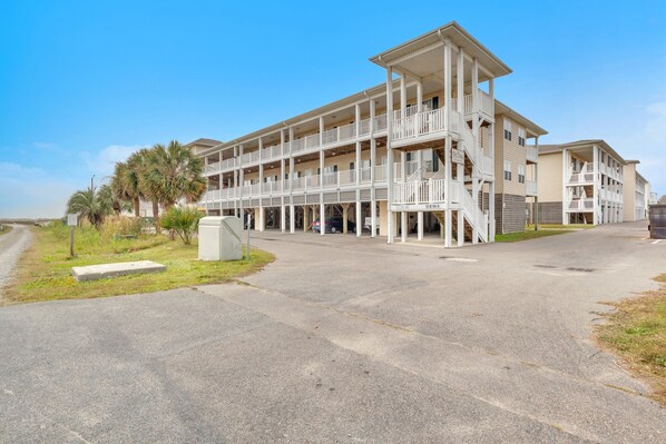 A multi-story hotel with balconies and a covered walkway.