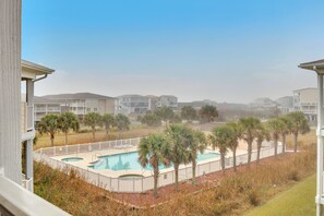 A residential area with a swimming pool surrounded by palm trees and a white fence.