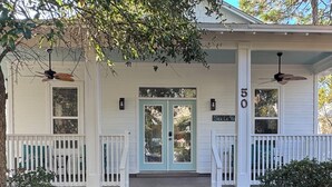 Uma casa de dois andares com varanda, porta azul e o número 50 na frente.