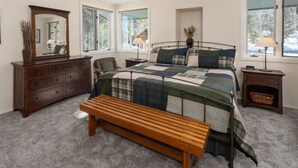 Une chambre à coucher avec un lit, un banc en bois, une commode, un miroir et une fenêtre.