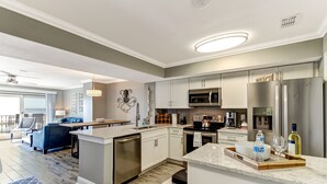A modern kitchen with stainless steel appliances, a central island, and a dining area with a blue sofa. - RENOVATED Ocean Front 2-story Condo  - Access to Amelia Island Golf & Beach Club (Fernandina Beach)