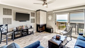 A living room with a TV, fireplace, and a balcony with a view of the ocean. - RENOVATED Ocean Front 2-story Condo  - Access to Amelia Island Golf & Beach Club (Fernandina Beach)
