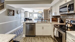 A modern kitchen with white cabinets, stainless steel appliances, and a patterned backsplash. - RENOVATED Ocean Front 2-story Condo  - Access to Amelia Island Golf & Beach Club (Fernandina Beach)