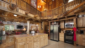 A spacious kitchen with wooden cabinetry, a large island, and a built-in stove.