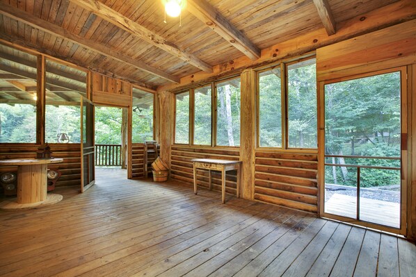 A log cabin with a wooden deck, large windows, and a rustic interior.