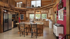 A spacious kitchen with wooden beams, a large island with bar stools, stainless steel appliances, and a red accent wall.