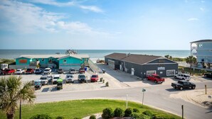 A parking lot with several cars, a building labeled "801 Ocean", and a view of the beach and ocean.