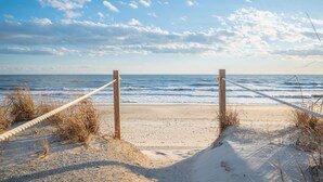 A beach with a rope barrier and wooden posts, leading to the ocean. - Sandy Dunes: Spectacular Oceanfront Home with Amazing Views (Oak Island)