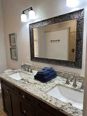 A bathroom with two sinks, a large mirror, and a towel rack.