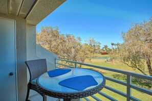 A balcony with wicker chairs and a glass table, overlooking a golf course and trees. - TOTALLY UPDATED, SPACIOUS/Clean, SEE MY RAVE REVIEWS! HIGHLY REQUESTED (St Petersburg)