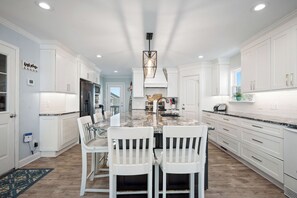 A kitchen with white cabinetry, a central island with chairs, and a pendant light.