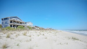 Een pand aan het strand met een meerlaags gebouw, een balkon en een zandstrand.