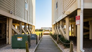 Un chemin en bois mène à un bâtiment sur lequel est apposée une pancarte indiquant que le stationnement est réservé aux propriétaires ou à leurs invités.