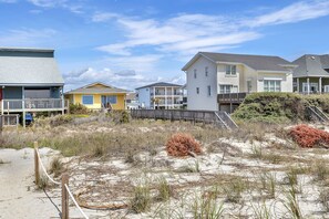 Un quartier résidentiel en bord de mer, avec des maisons, une plage de sable et une clôture en bois.