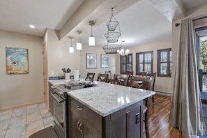 A kitchen with a marble island, wooden cabinets, and pendant lighting. - Park Place Quandary Peak Condo: Ski-in, Downtown Breck (Breckenridge)