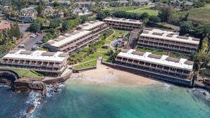 Un hôtel situé sur la côte, composé de plusieurs bâtiments, avec une plage et un rivage rocheux.