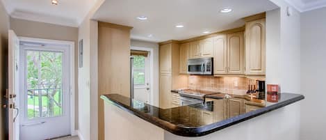 A kitchen with a central island, recessed ceiling lights, and wooden cabinets.