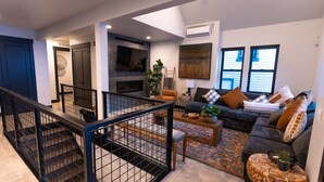 Ein modernes Wohnzimmer mit einem dunkelgrauen Sofa, einem Couchtisch und einer Treppe mit schwarzer Geländer.