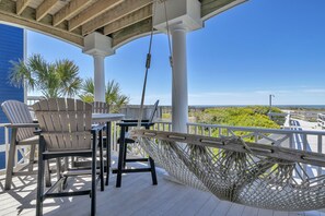 A covered outdoor area with a wooden deck, white chairs, a table, and a hammock. - Surviving Stress: Exquisite Oceanfront Caswell Beach Home Perfect for Small Beac (Caswell Beach)
