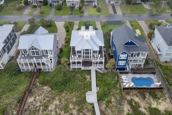 Vue aérienne d’un quartier résidentiel avec des maisons, une piscine et un petit pont.