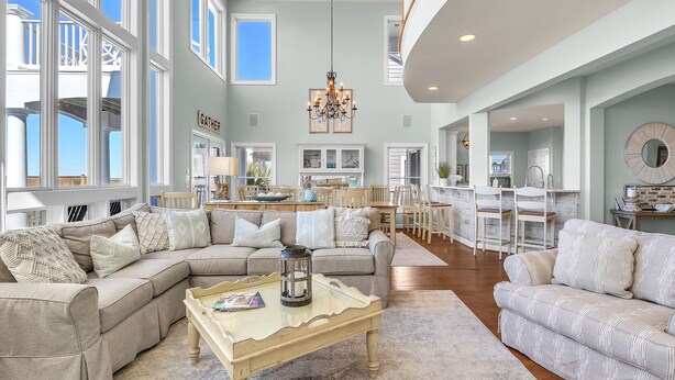 A spacious living room with a large sectional sofa, a coffee table, and a chandelier. - Surviving Stress: Exquisite Oceanfront Caswell Beach Home Perfect for Small Beac (Caswell Beach)