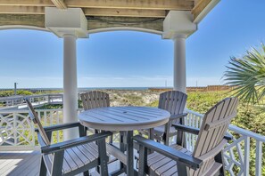 A covered outdoor seating area with a table and chairs, overlooking a beach. - Surviving Stress: Exquisite Oceanfront Caswell Beach Home Perfect for Small Beac (Caswell Beach)