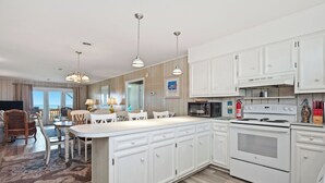 Een moderne keuken met witte kastjes, een groot eiland en een ingebouwde oven.
