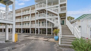 Un hotel de varios pisos con balcones, una escalera central y un área de estacionamiento.