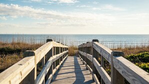 A wooden boardwalk leading to a beach with a clear sky. - Caswell Cabana: Oceanfront, Split Floor Plan, Views of Lighthouse (Caswell Beach)