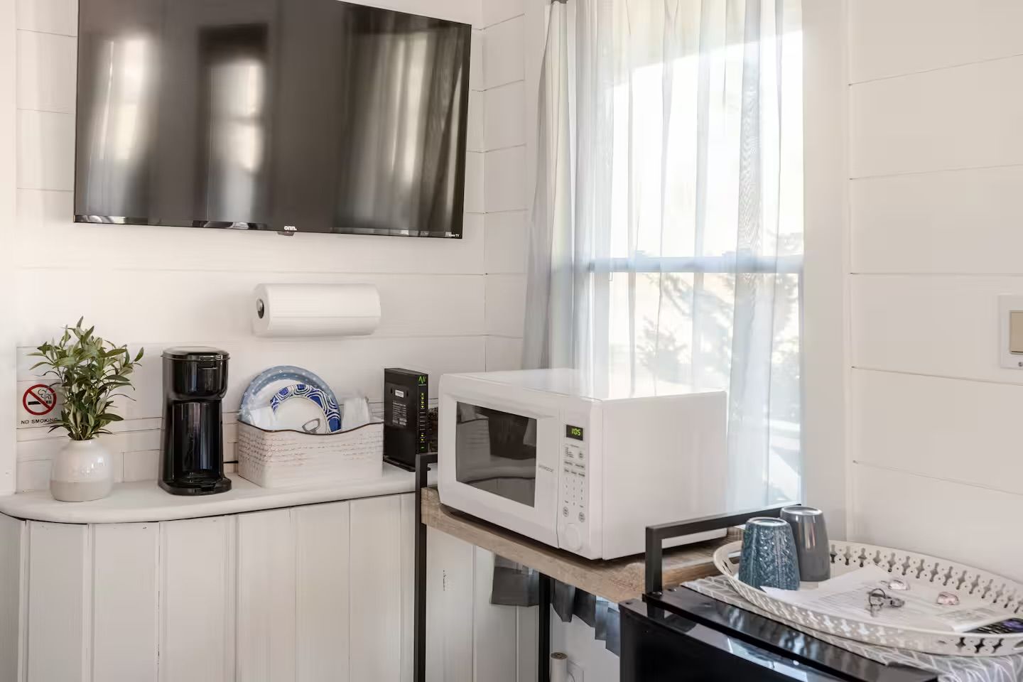 Une cuisine équipée d’un four à micro-ondes, d’une machine à café et d’une plante.