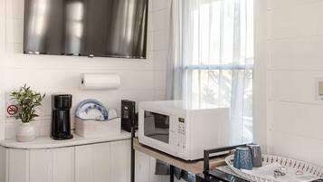 Une cuisine équipée d’un four à micro-ondes, d’une machine à café et d’une plante.