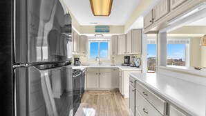 Una cucina moderna con mobili bianchi, un frigorifero nero e un pavimento in legno.