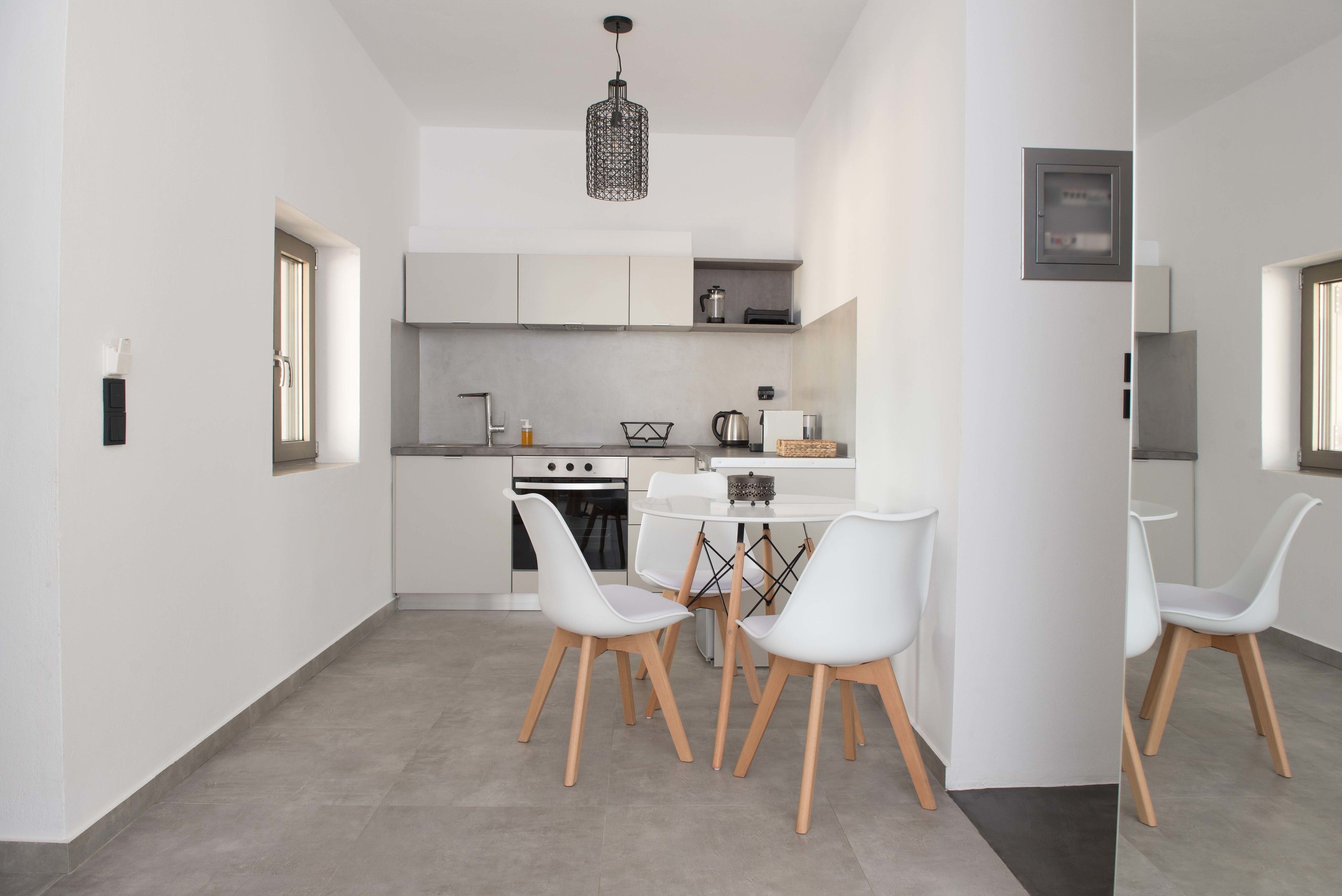 A modern kitchen with white cabinetry, a central island, and a hanging light fixture.
