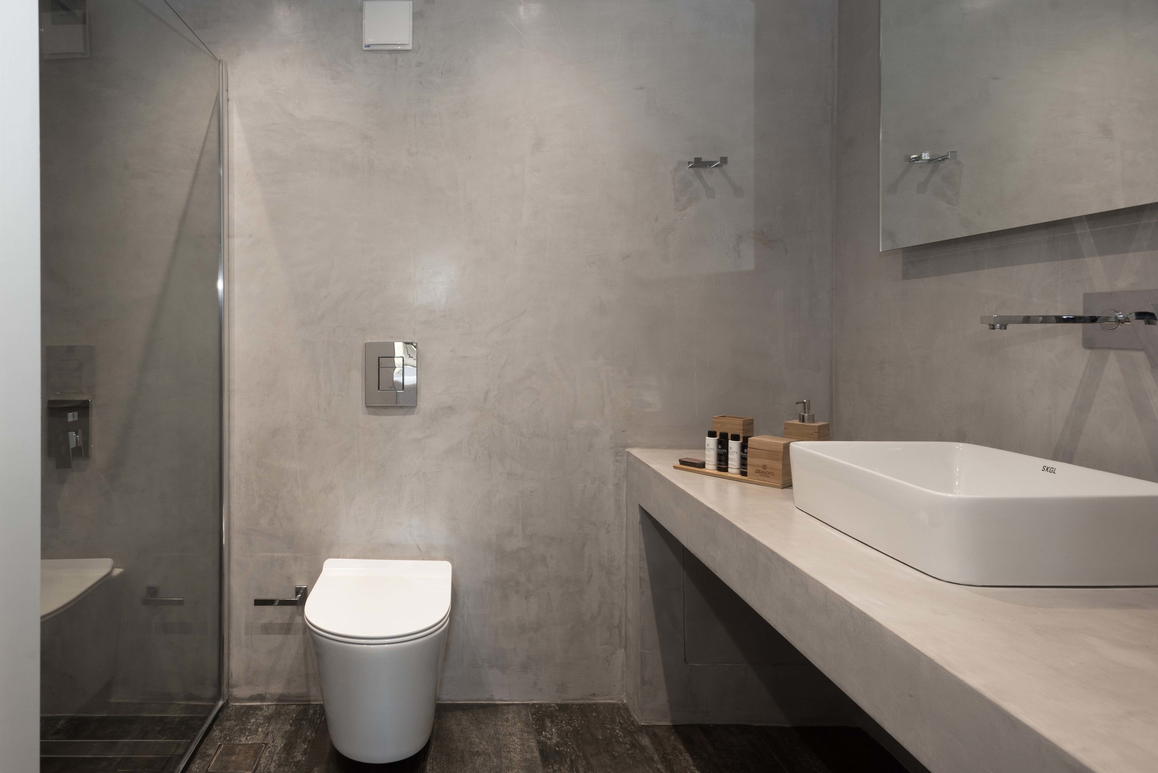 A modern bathroom with a toilet, a shower enclosure, and a large white sink.