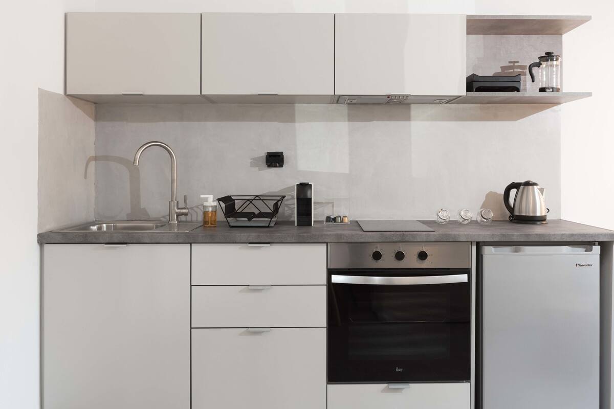 Una cocina compacta con horno integrado, lavavajillas y cafetera.