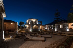 A stone building with a patio area featuring lounge chairs and a fire pit. - Calme Suites Mani (West Mani)