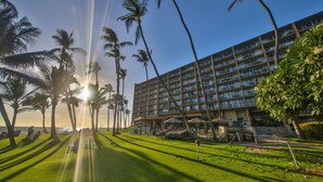 A hotel with a large building, palm trees, and a grassy area.
