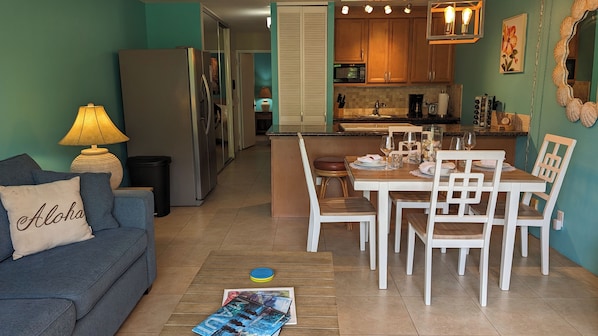 Un espacio habitable compacto con kitchenette, comedor y sofá con cojín.