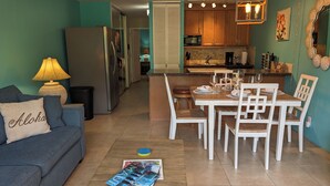 A compact living space with a kitchenette, a dining area, and a sofa with a cushion. - Maui Vista #2-101 Ground Floor, Pickle Ball Courts, Near Kamaole Beach Park (Kihei)