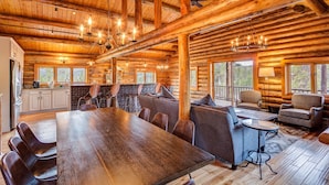 Een ruim interieur van een vakantiehuis, met een grote eettafel, comfortabele zitplaatsen en een keukenhoek.