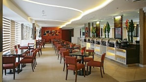 A modern restaurant with a long counter, multiple tables, and chairs.