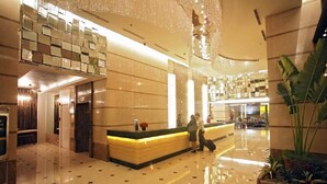 A spacious lobby with a high ceiling, a reception desk, and a large plant.