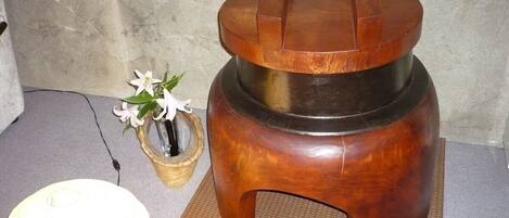 A wooden stool with a circular top and a flat base, placed on a textured mat.