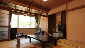 A traditional Japanese room with tatami flooring, a low table, a sofa, and a television. - Akao-Kan (Nanto)