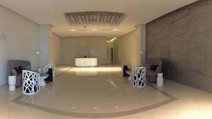 Eine großzügige Lobby mit Empfangstresen, modernen Stühlen und einer dekorativen Decke.