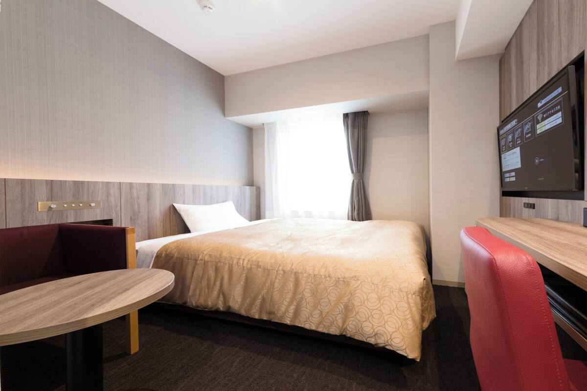 Une chambre d’hôtel moderne équipée d’un lit, d’un bureau, d’une chaise et d’un téléviseur.