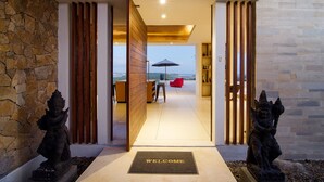 A modern entrance with a stone wall, wooden slats, and a welcome mat. - Villa Bliss (Kuta)